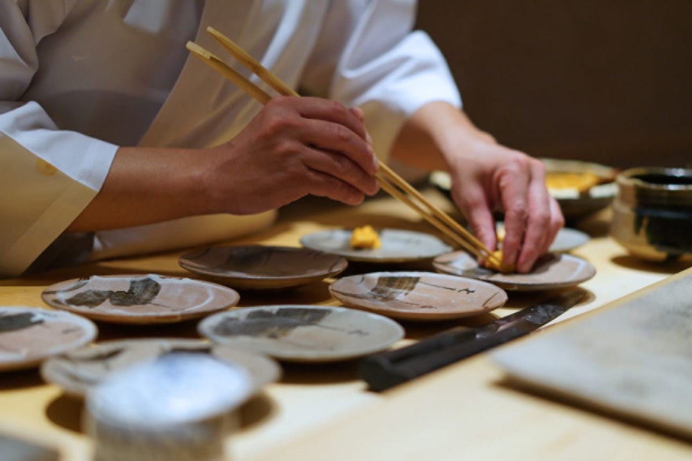 Sushi Saito chef plating up dishes